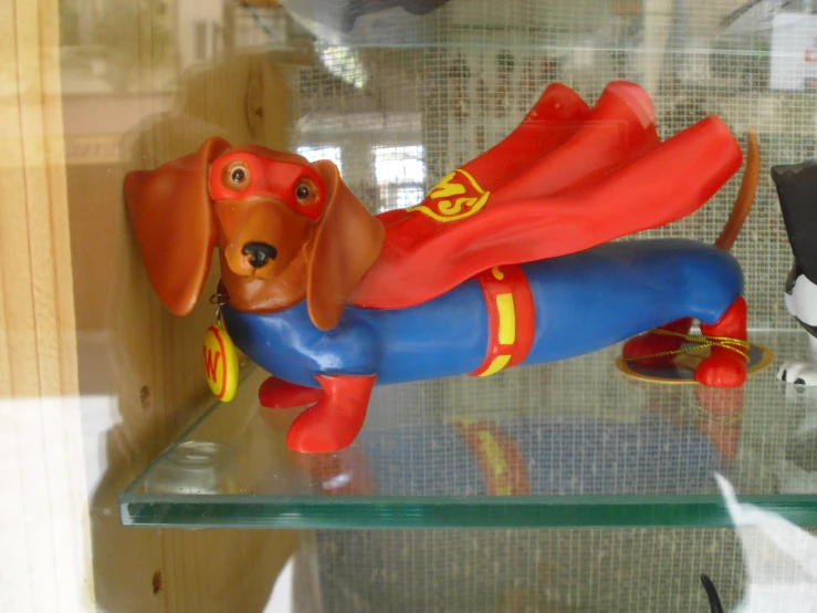 a stuffed toy dog with a red suit on laying on its side