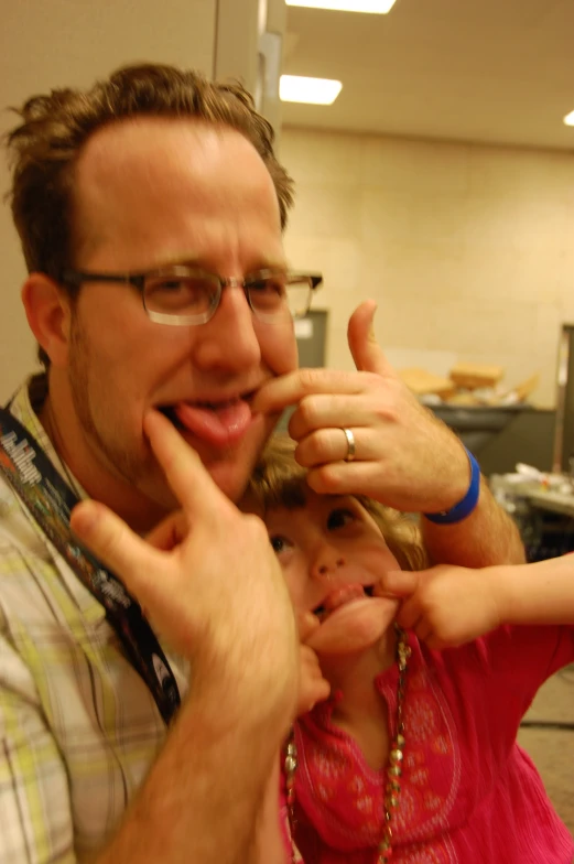 a man with a ring on his left hand holding a small girl's finger up to the mouth