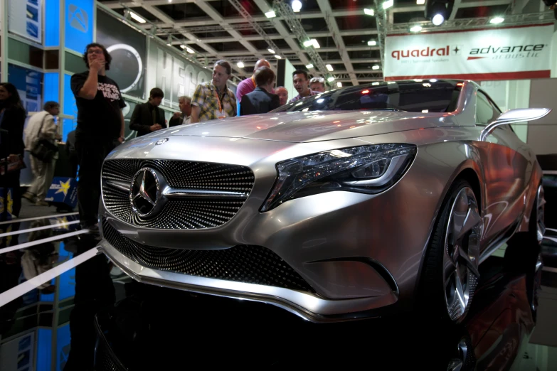 a mercedes vehicle sitting on display next to people