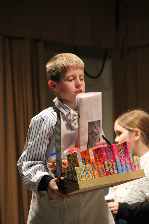 a boy holds books that have a box containing some candy