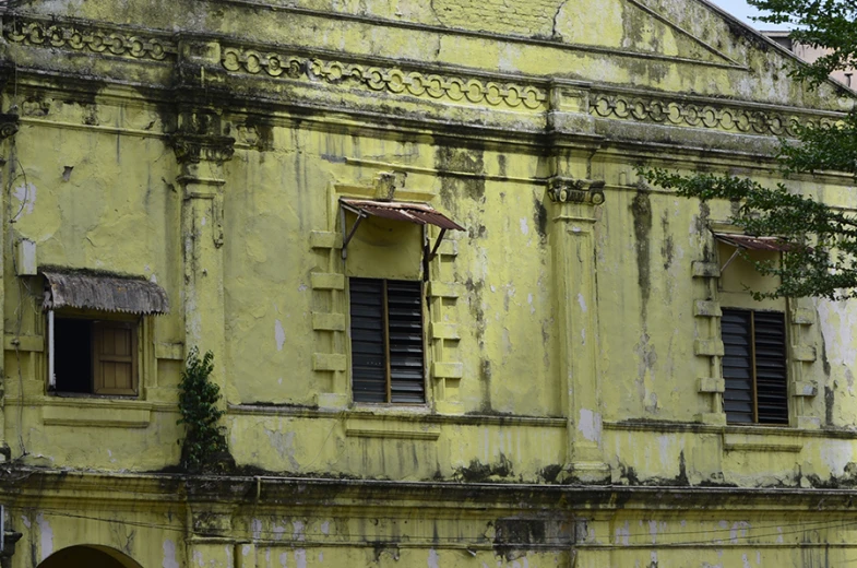 an old, crumbling yellow building with windows and shutters
