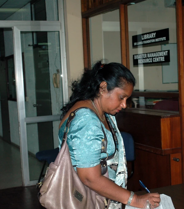 a woman holds a book and writes on a piece of paper