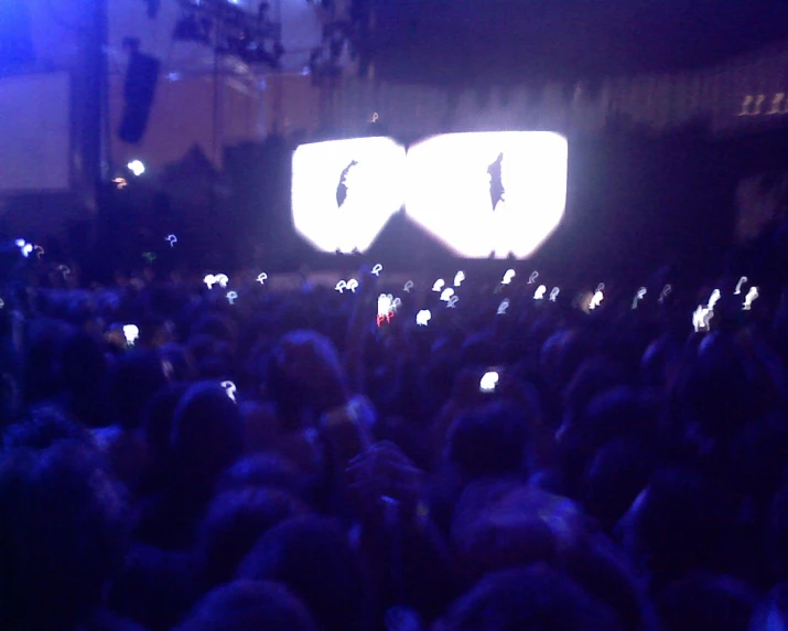 a crowd is holding up their phones in the dark