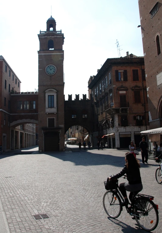 a person riding a bicycle past a brick building