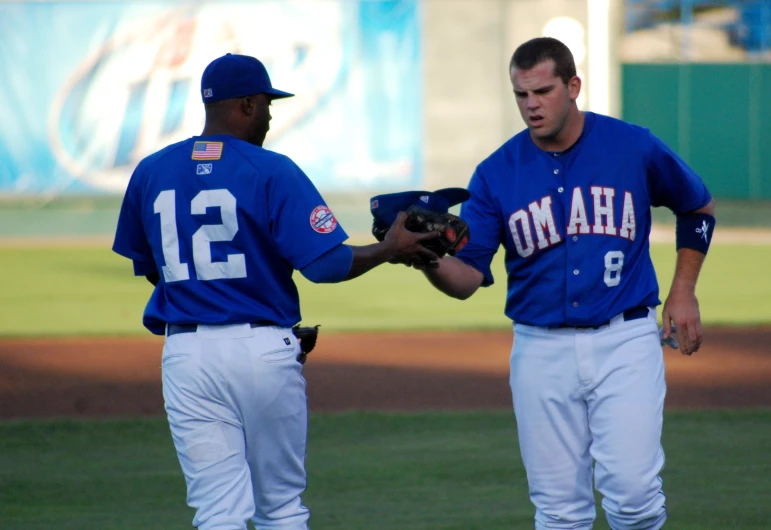 two baseball players shaking hands on the field