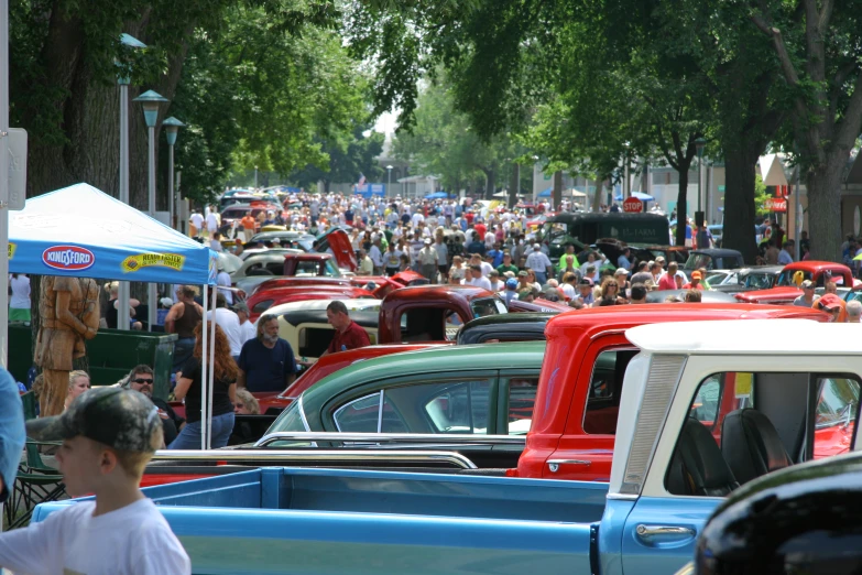 rows of cars in a street with a crowd behind them