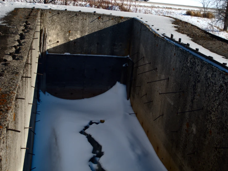 a small water tank filled with snow next to a field