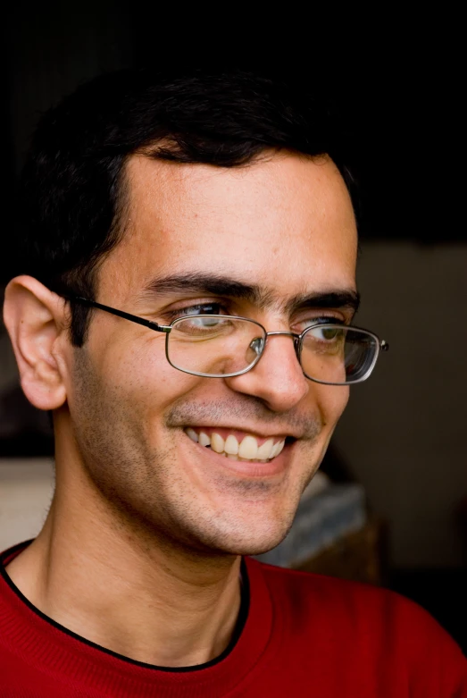 a man wearing glasses smiling for the camera