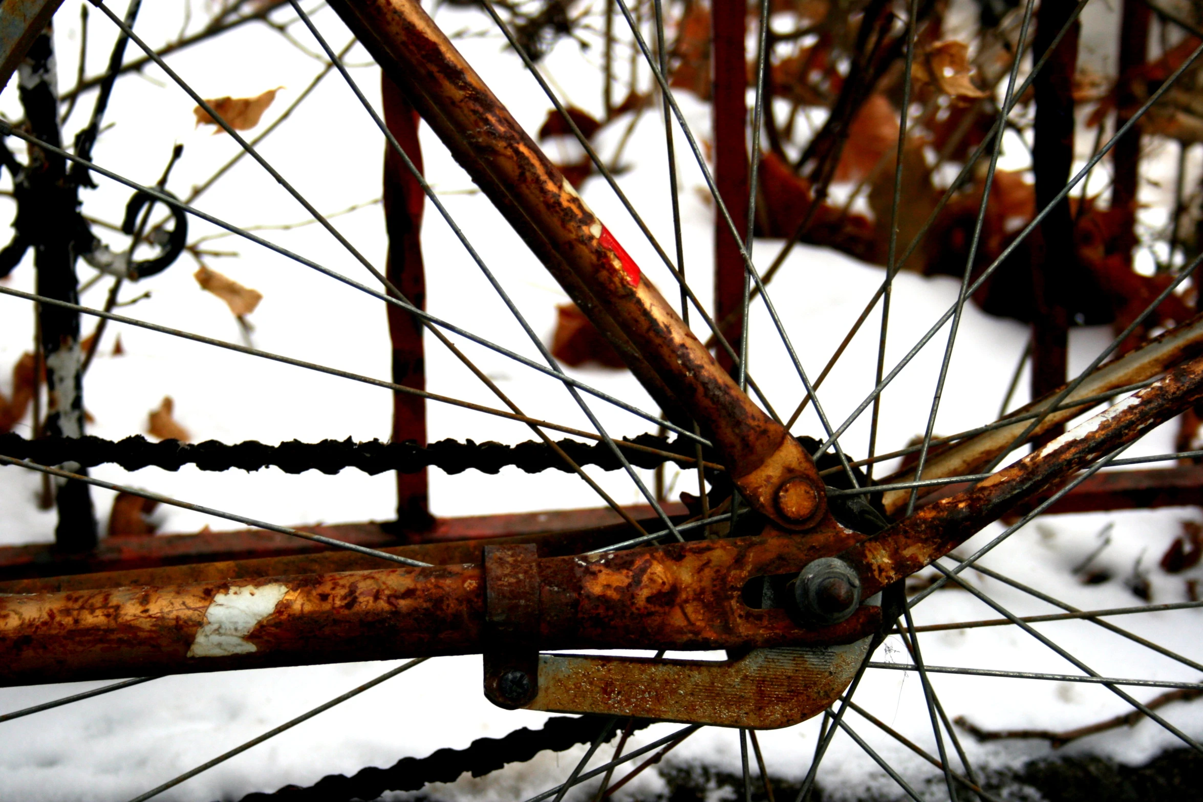 the spokes and sides of a rusted bicycle on snow covered ground