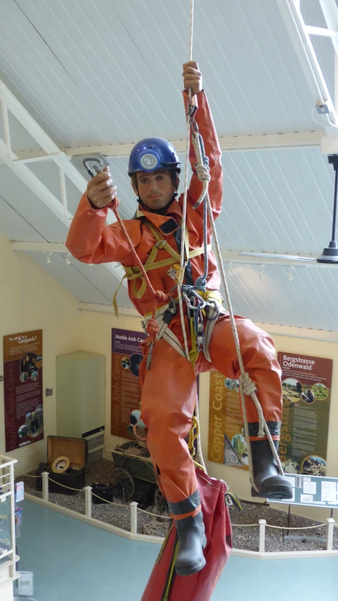 a man wearing an orange uniform and helmet while being rappeld on a rope