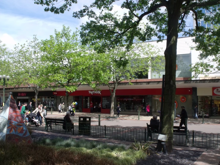 an outdoor shopping mall filled with people and trees