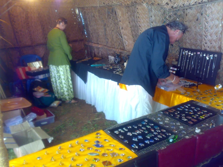 people stand around tables with many items on it