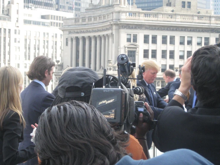 man in suit and tie surrounded by media and people