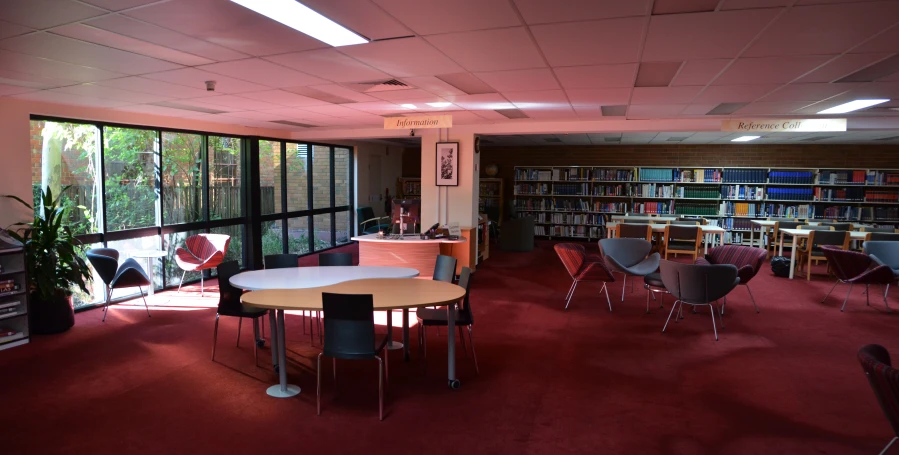 a room with tables, chairs, and books