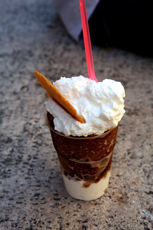 a person is holding a straw and a drink with whipped cream on top