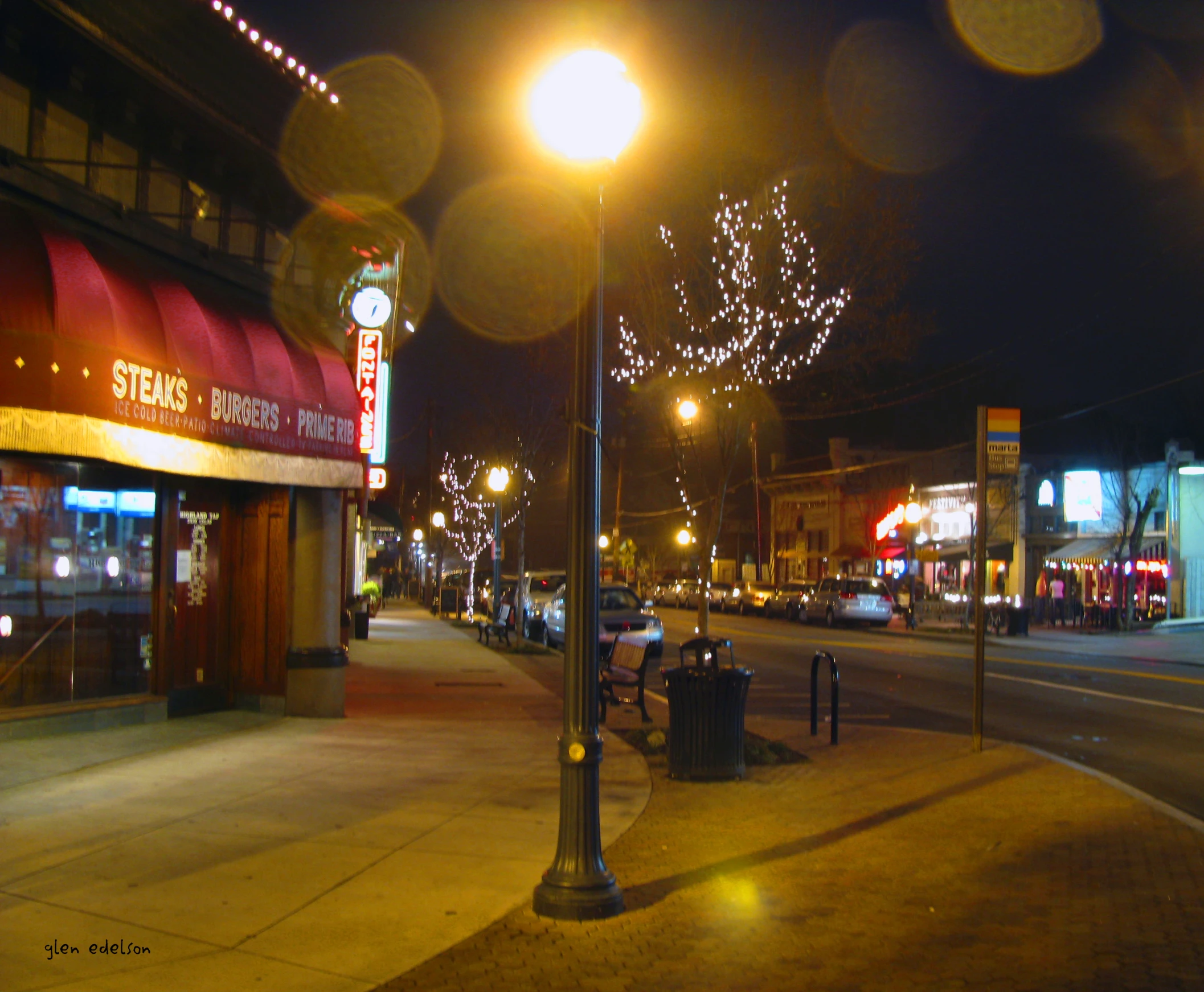 a street filled with traffic and buildings covered in christmas lights