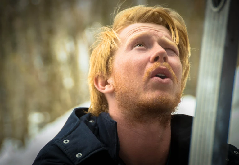 a person with an orange beard stares upward