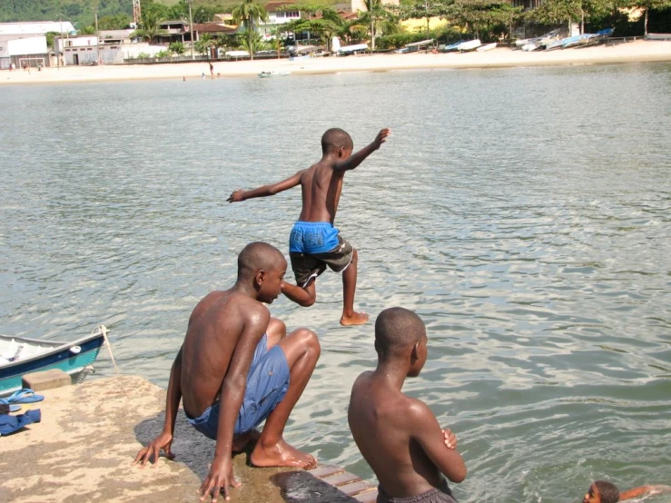 three boys jumping into the water from a dock