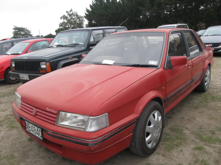 red cars parked at a car show in the dirt