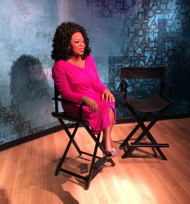 a woman in a pink dress sitting on a chair