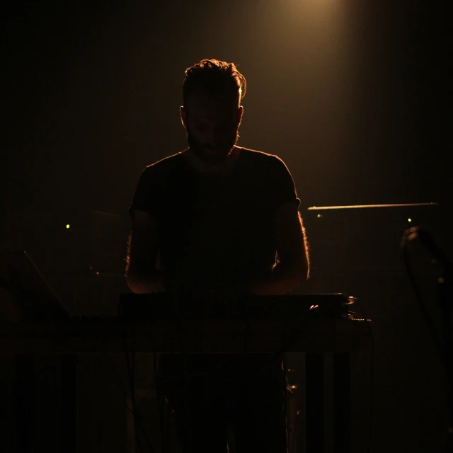 a man playing keyboards while standing in the dark