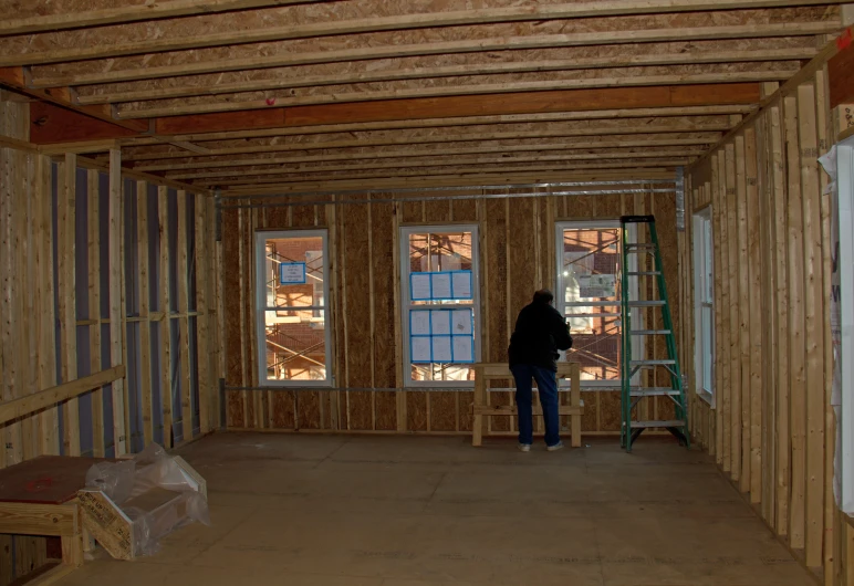 a woman standing in front of a window in a room being built