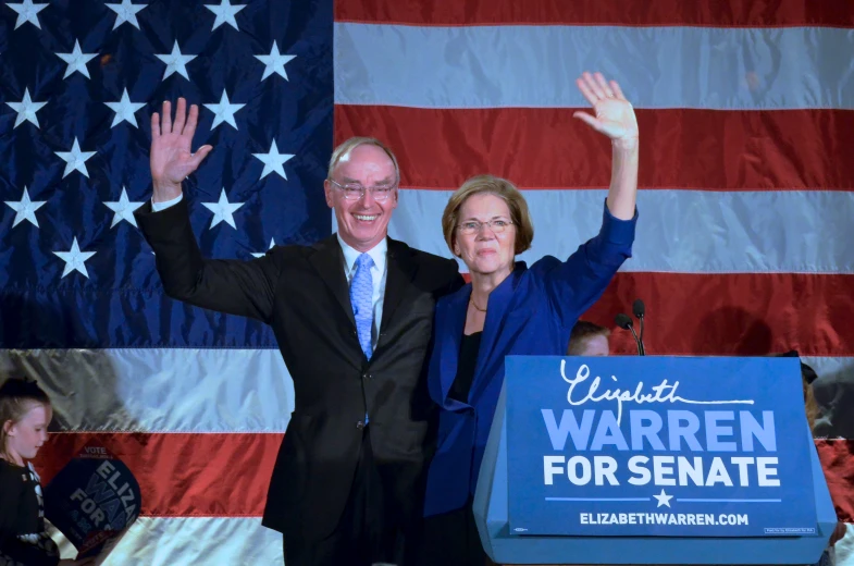 two people in suits and ties standing behind a blue sign