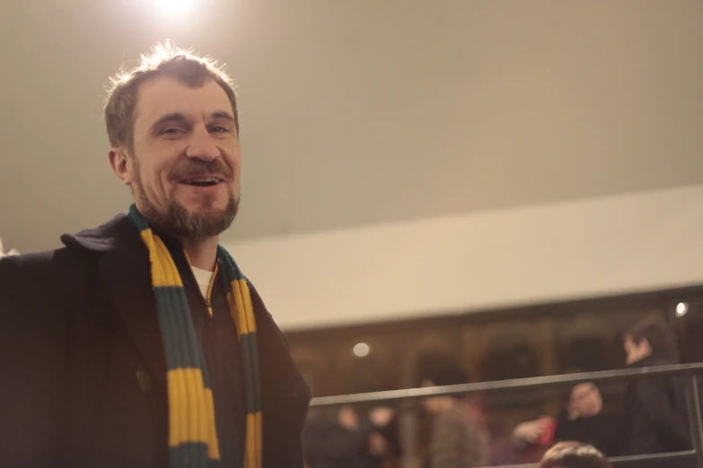 a man with a black sweater and a yellow and green scarf