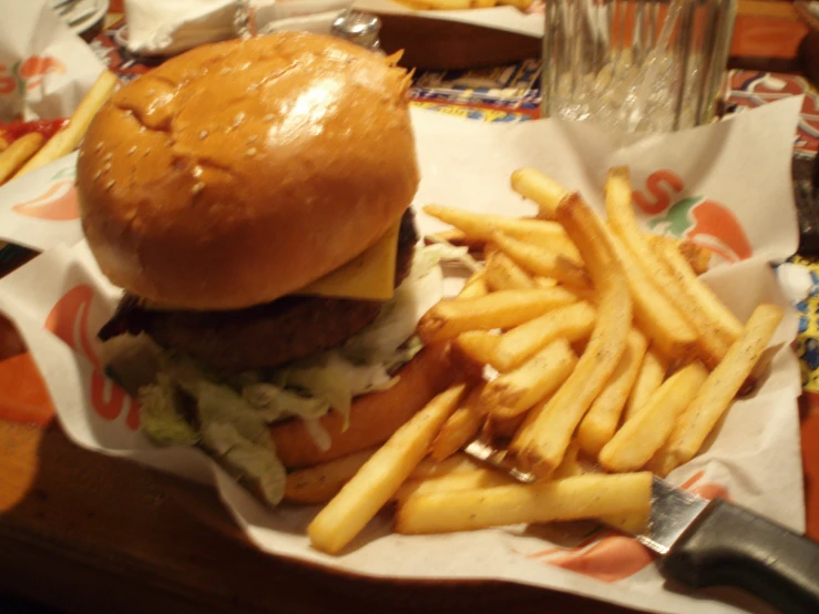 a hamburger and fries on paper with a drink