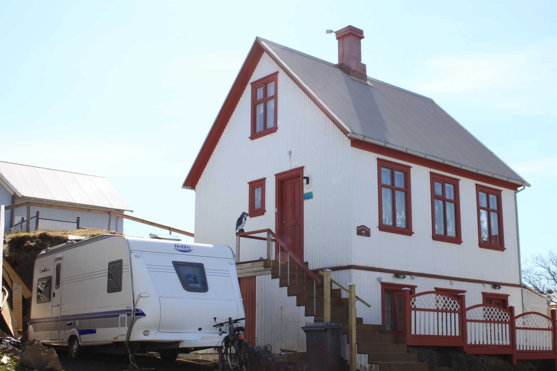 a white house with a red trim sits next to a truck and a trailer