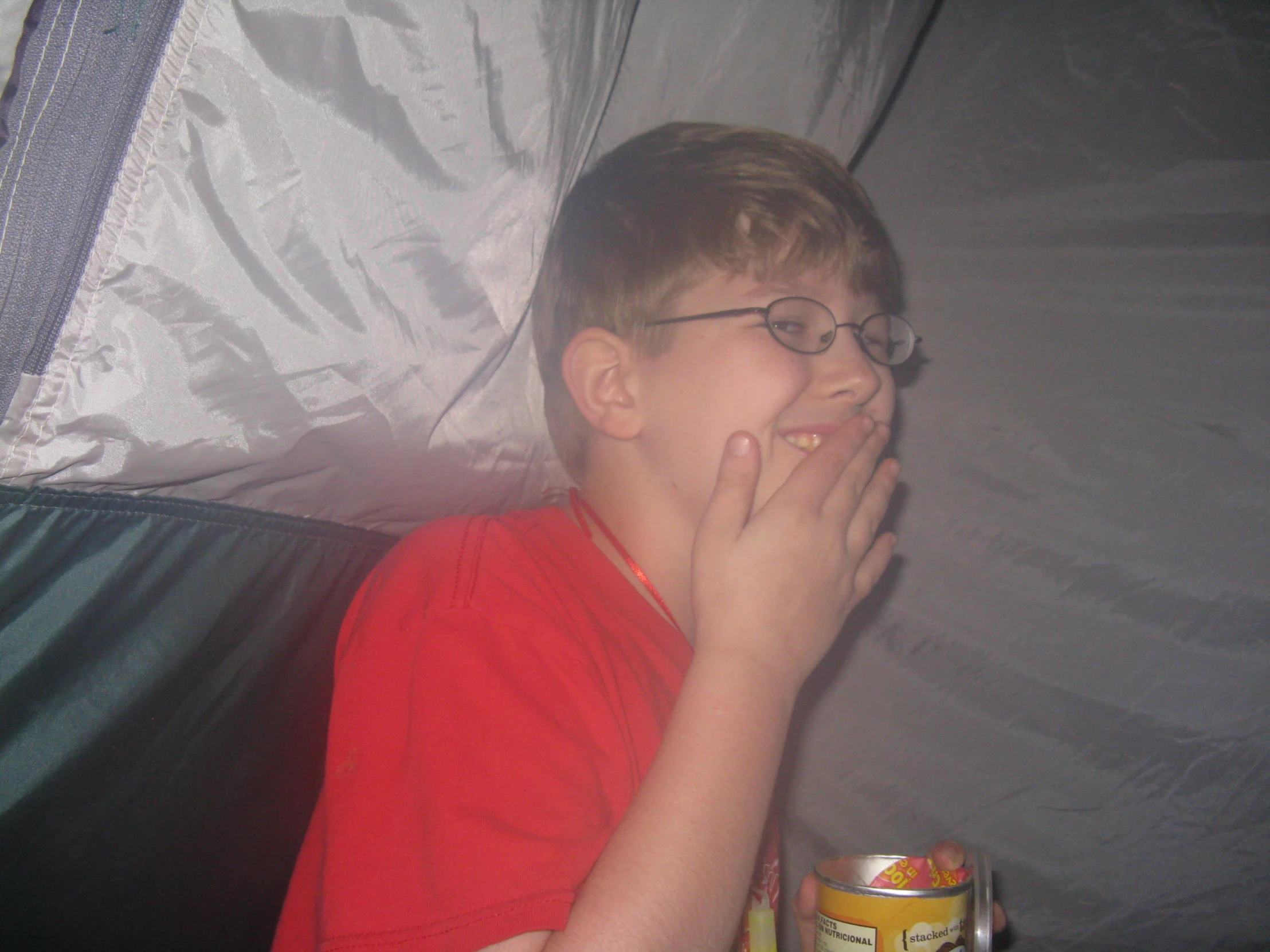 a young child in glasses with food in his mouth