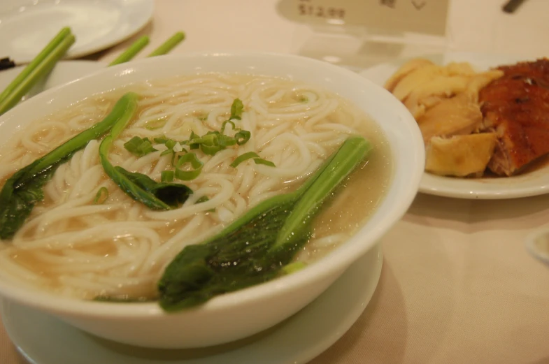 a bowl of ramen and vegetables are on a table