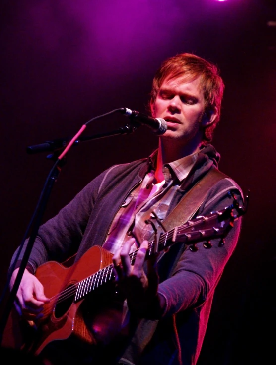 a man holding a guitar in front of a microphone