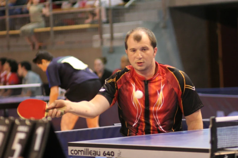 man holding paddle in both hands, preparing to throw ping pong