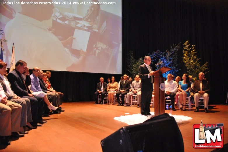 a man standing at a podium while speaking to people