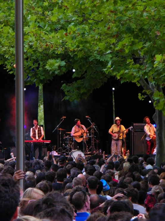 a group of people in front of a crowd playing on guitars