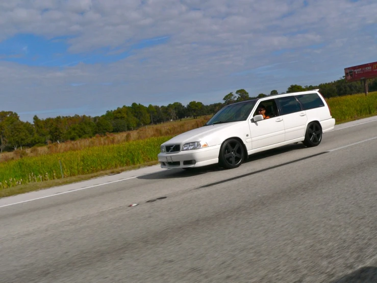 white car on the road passing through grass