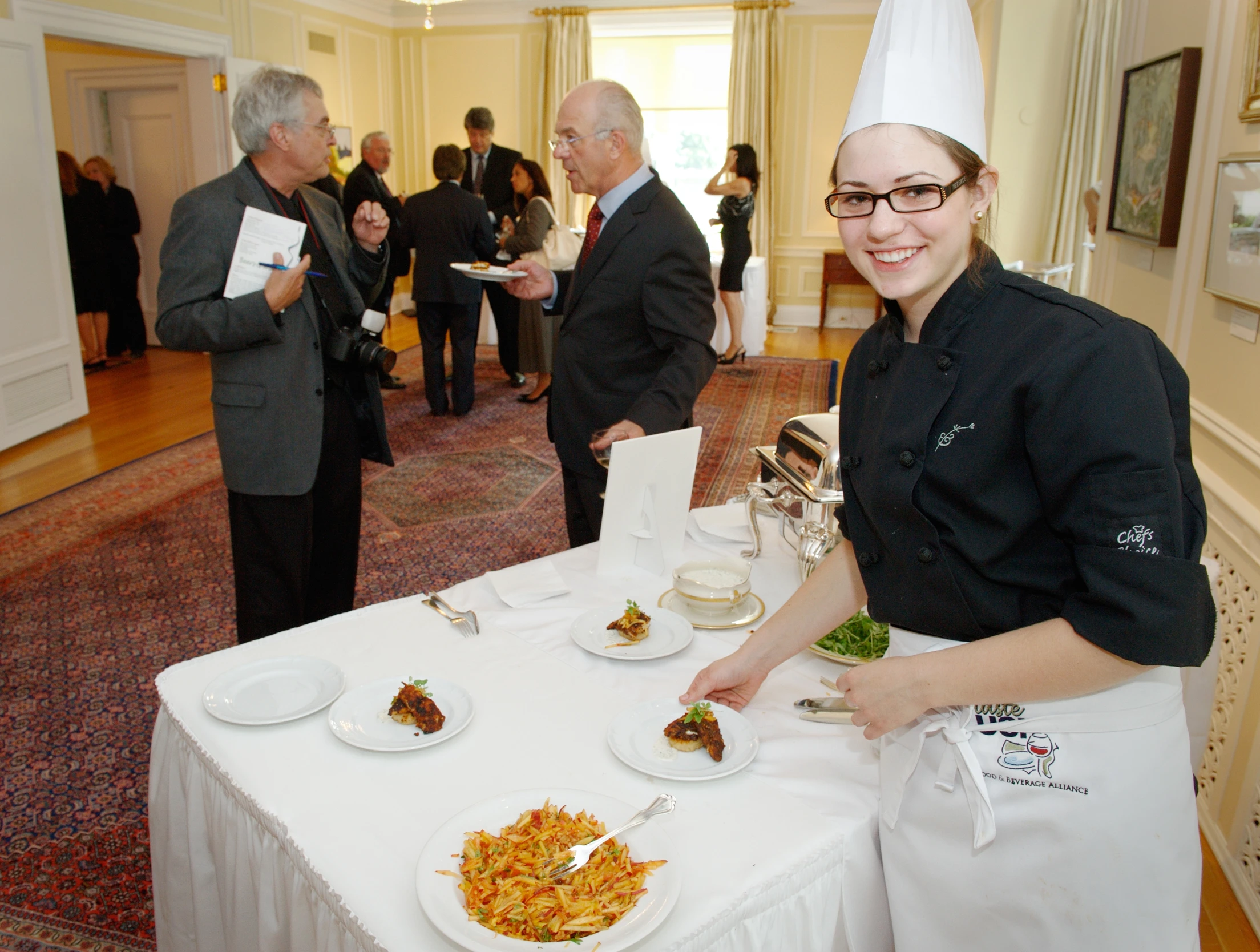 a person with a chef hat standing next to a table full of plates of food