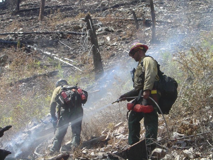 two firemen using hoses to put out a controlled fire