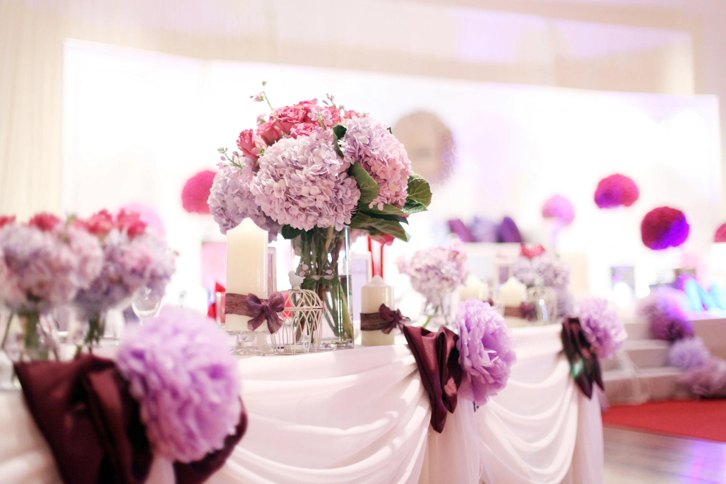 the table has purple and white flowers in vases