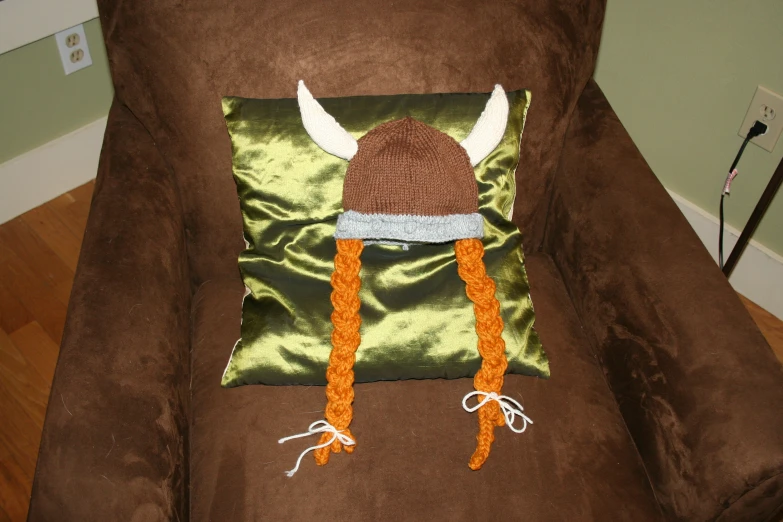 the brown couch has a decorative pillow and a hat