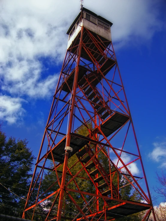 a fire tower is against a blue cloudy sky