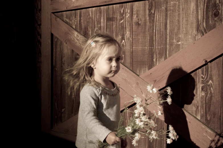 a little girl holding a bouquet of flowers by a door