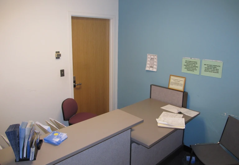 an empty office with a brown desk and blue walls