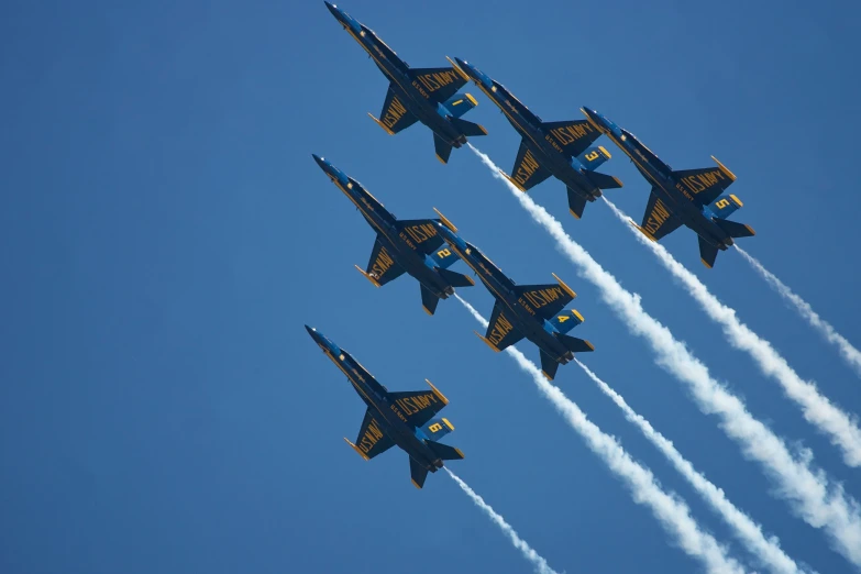 four fighter jets flying in formation in a blue sky