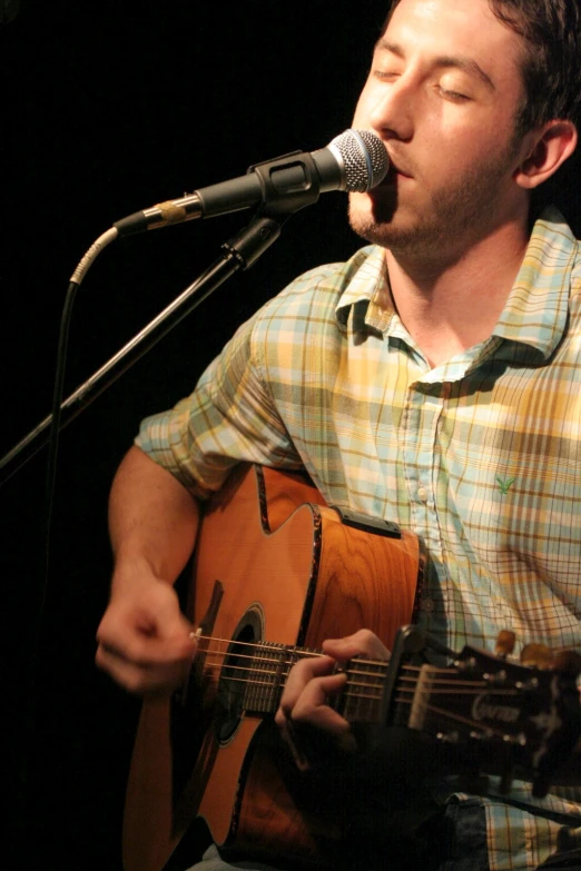 a man is holding a guitar while singing