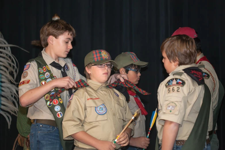 three scout boys with scout badges and one man has his arm folded open