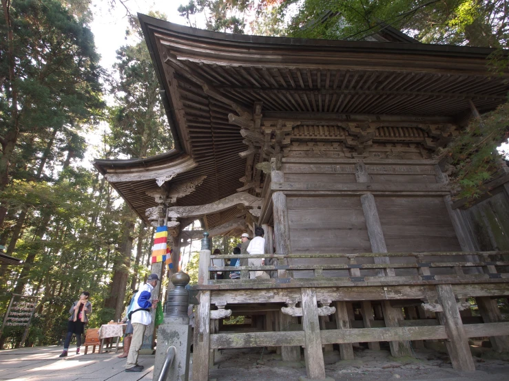 people walking near a carved wooden structure in the woods