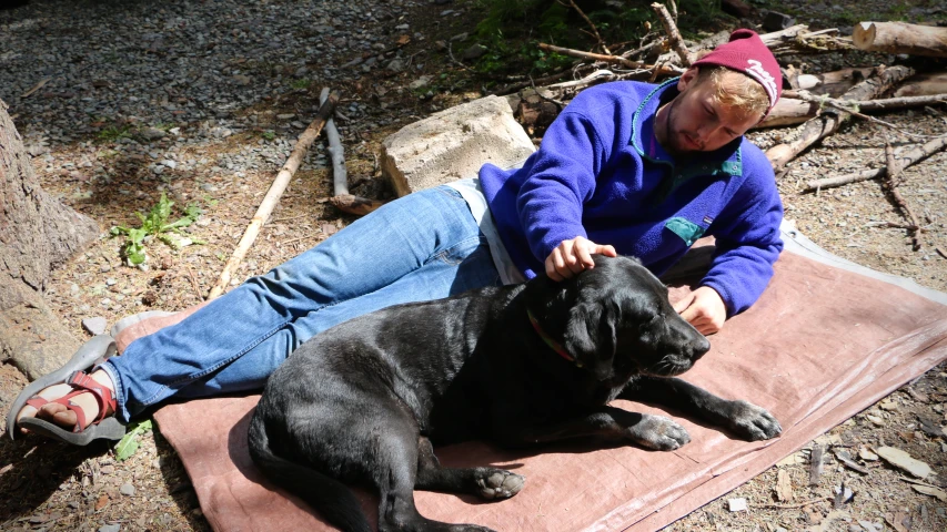 a woman sitting down with her dog on the ground