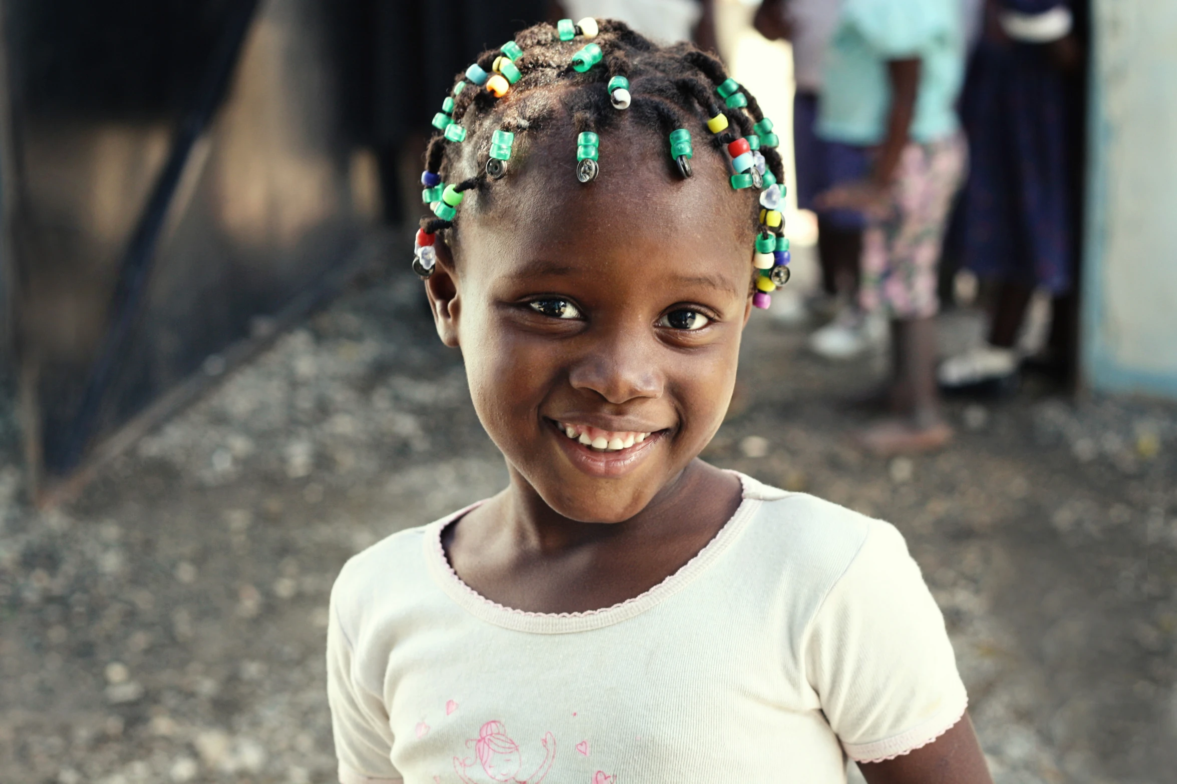 a smiling  has green and yellow beads on her hair